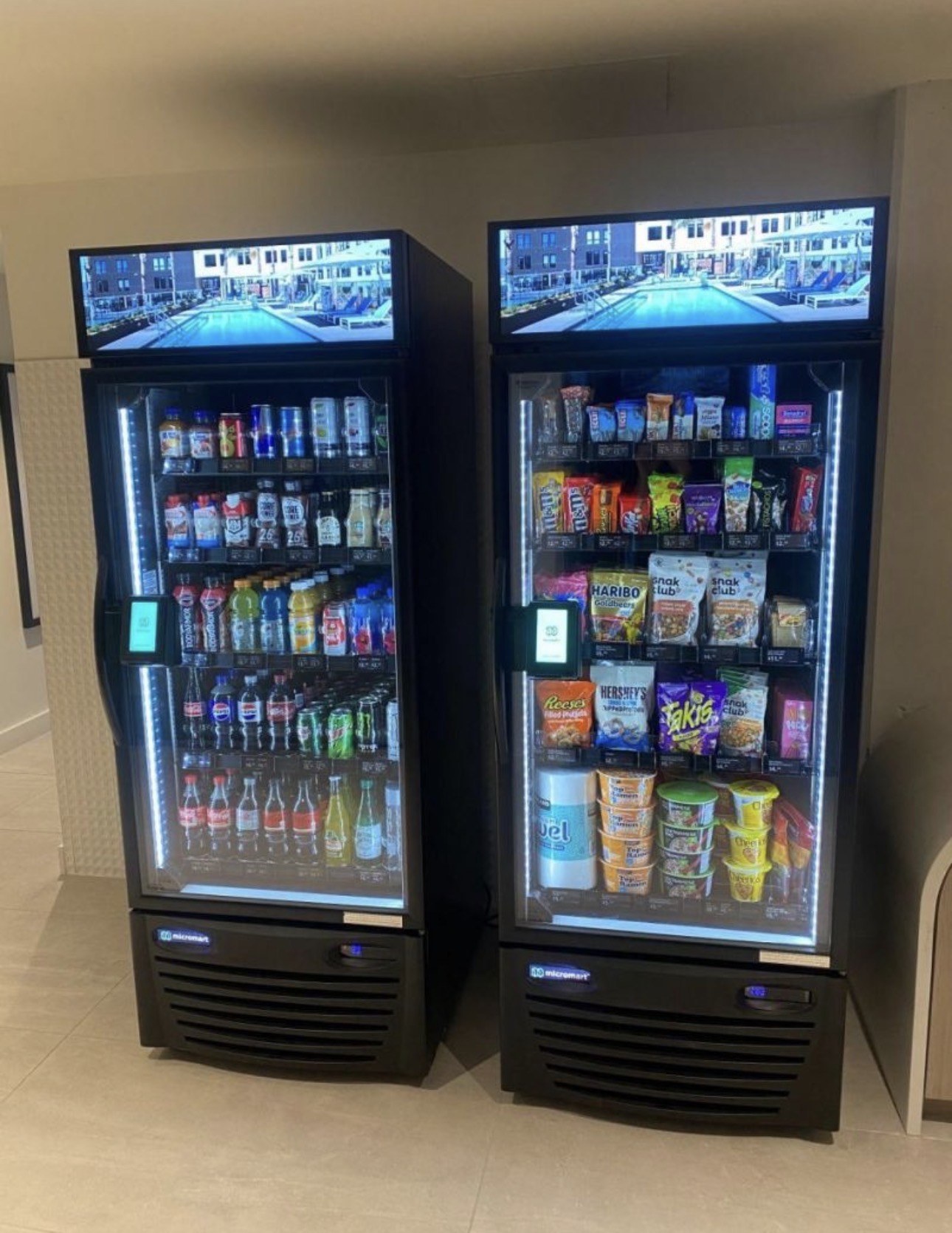 Two premium smart coolers installed side-by-side in a residential lobby with digital displays showing resort amenities